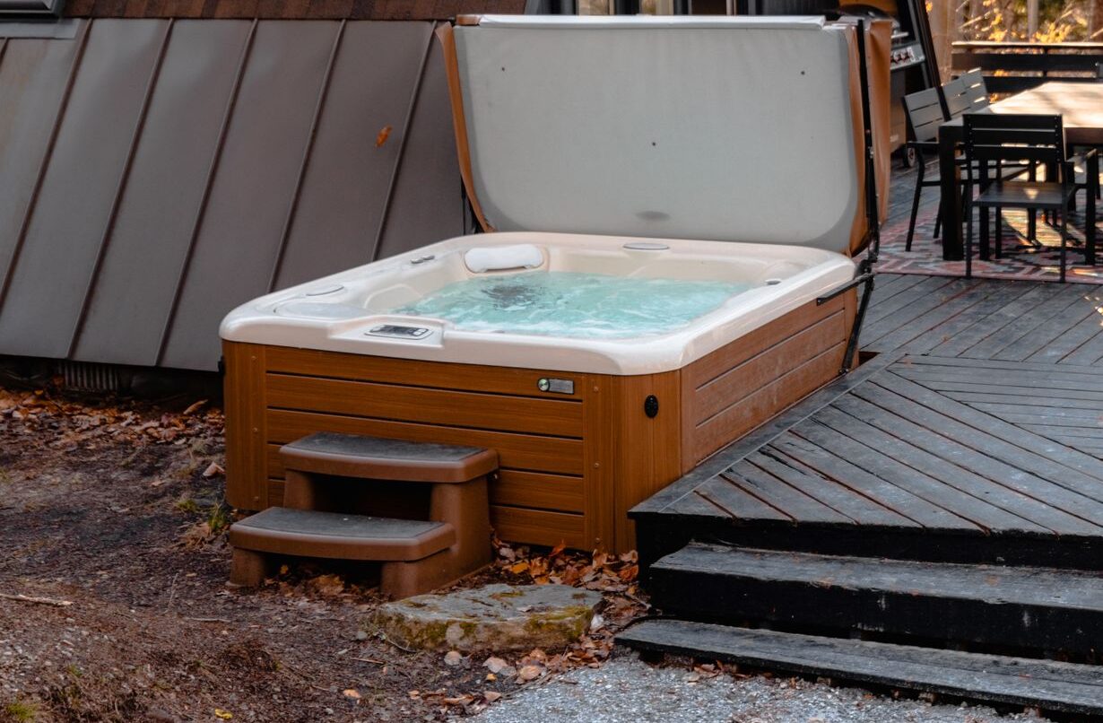 Charming A-frame cabin in Stowe, VT with outdoor hot tub and sauna surrounded by trees.