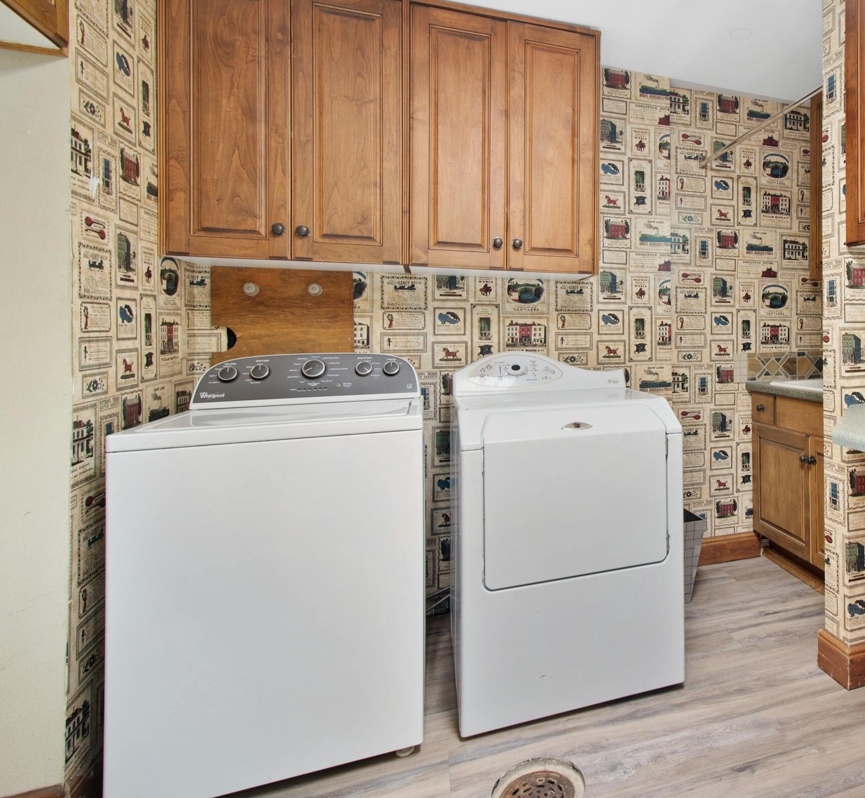 Cozy laundry room with wooden cabinets, washer, and dryer setup.